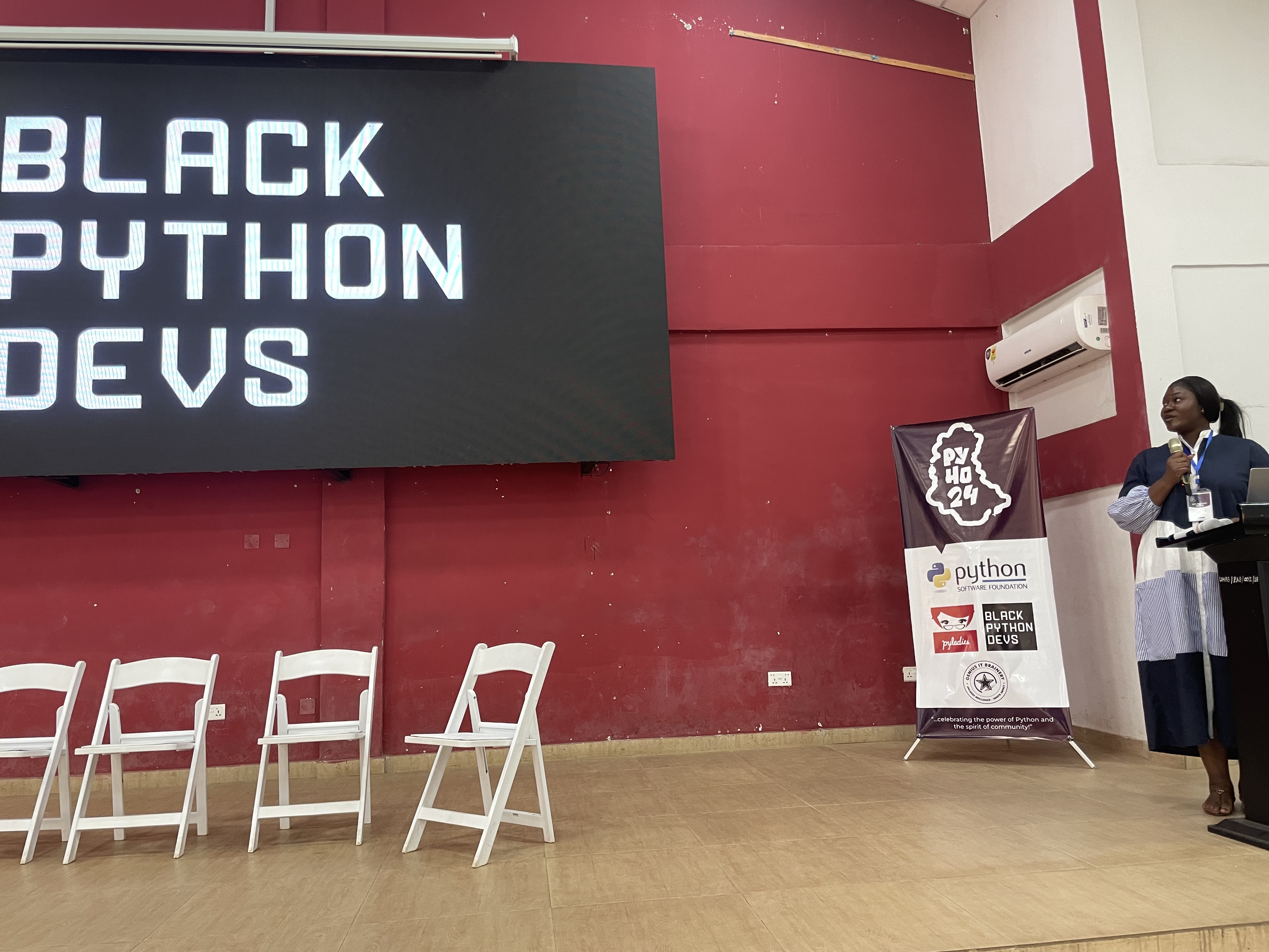 Woman on stage looking at Black Python Devs Logo on screen